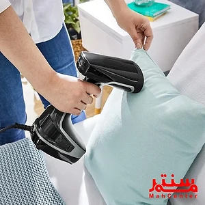 فردی در حال استفاده از یک دستگاه بخارشوی دستی برای بخارشوی یک بالش آبی رنگ